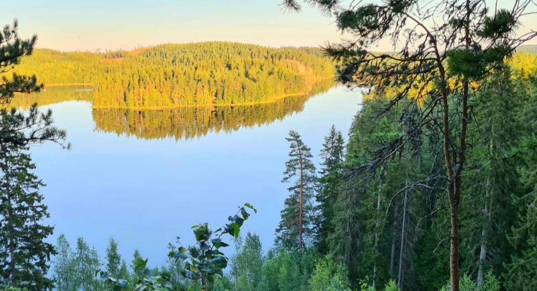 Kuhmoisten Linnavuorelta aukeaa näkymä tyynelle järvelle ja vastapäisen rannan metsikköihin ja saariin.