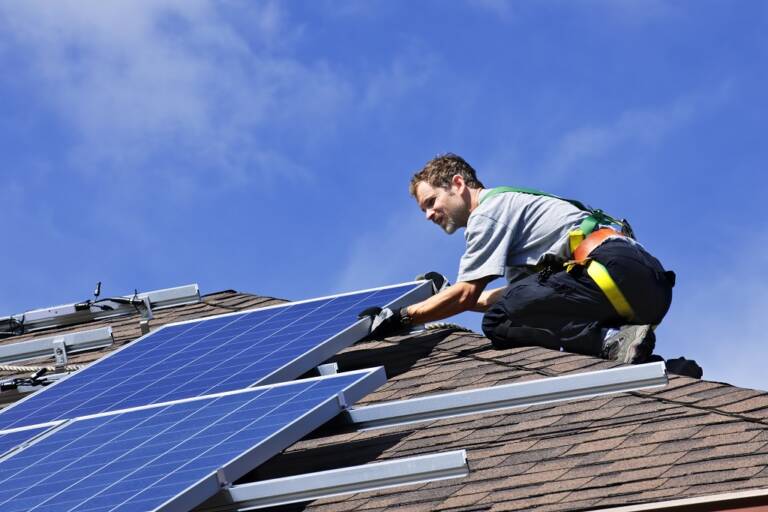 Mies katolla asentamassa aurinkopaneeleja